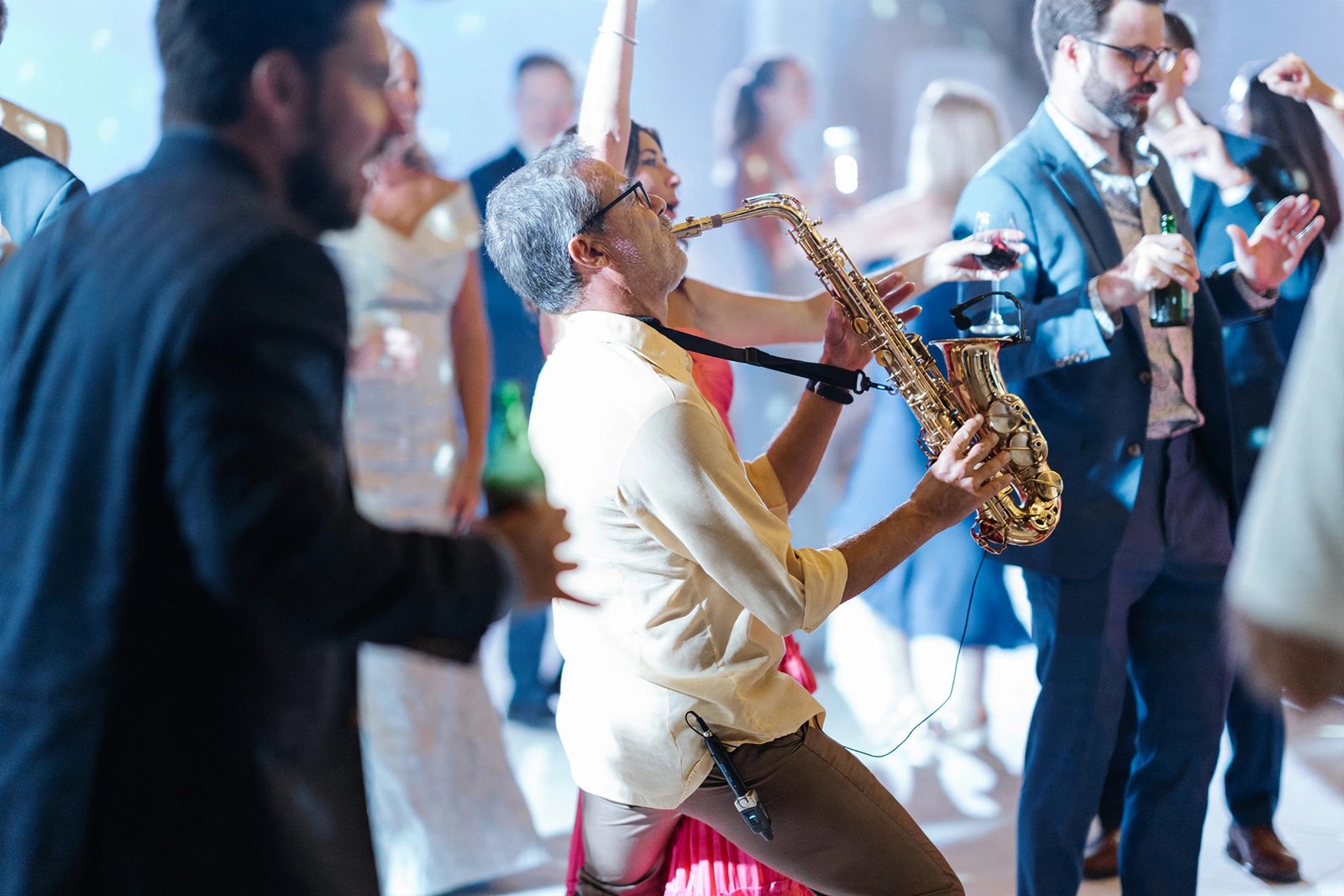Wright playing saxophone live in the middle of a wedding dance floor, guests dancing around him
